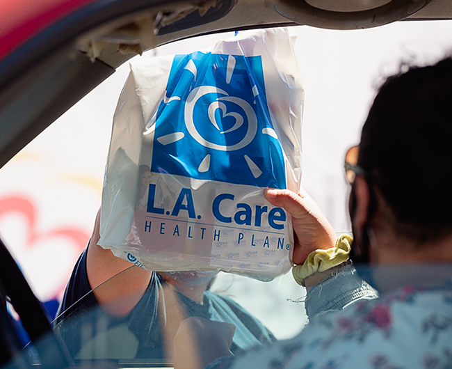 an L.A. Care bag handed to person in car