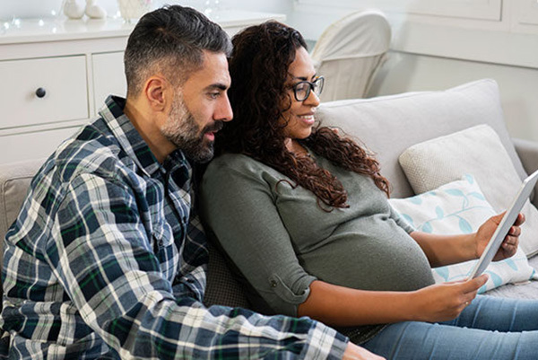 man and pregnant woman looking at tablet